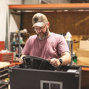 A Parts Express employee installing a large driver into an enclosure.