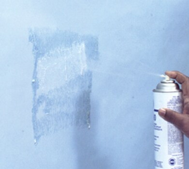 Image of step 2, adhesive spray applied to the wall surface.