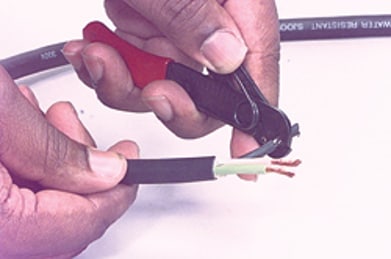 Using a wire stripper to remove insulation from the conductors